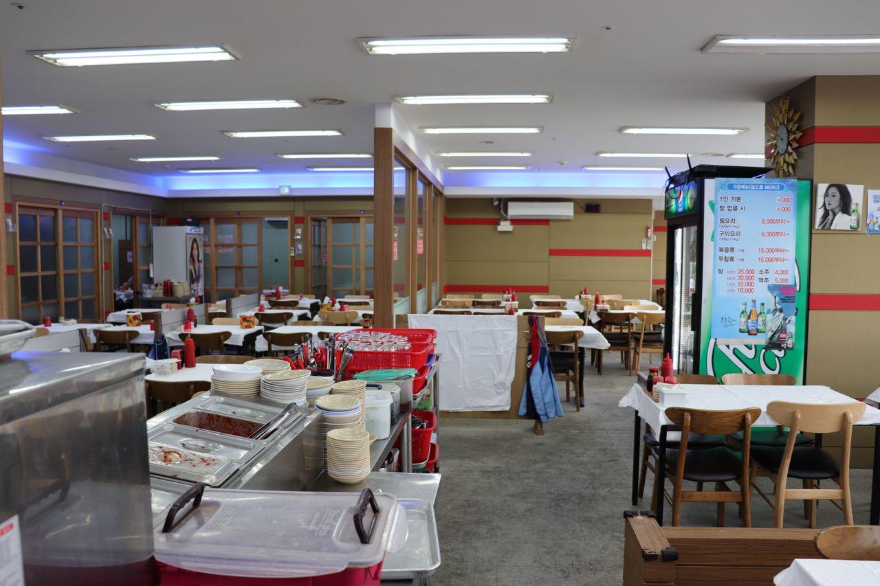 Interior de la Casa de Pescado Ilbeonji en el Mercado de Pescado de Noryangjin, mostrando mesas y área de servicio.